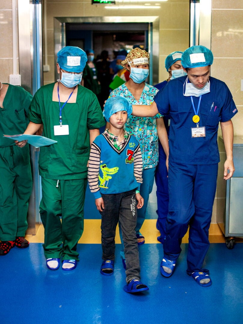 Shijun bravely walks into the operating room with anaesthesiologist Dr. Daniel Kim of Brazil. Photo: Zute Lightfoot