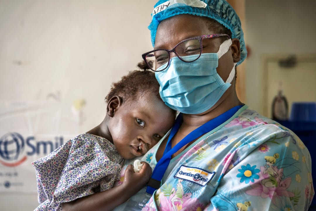 Operation Smile's child life specialist, Cathy Cheonga, comforts Gertrude, before her cleft surgery.