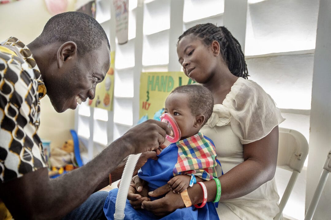 Child life specialist Charles from Ghana teaches Yaw how to use the anaesthesia mask before surgery. Photo - Zute Lightfoot