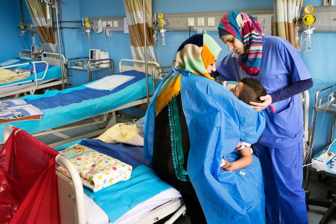 Eight-year-old Abdel  in his mother's arms after cleft surgery assisted by Volunteer Recovery Room Nurse Buthaina Abu Al-Shaikh. Photo: Manuela Emmer