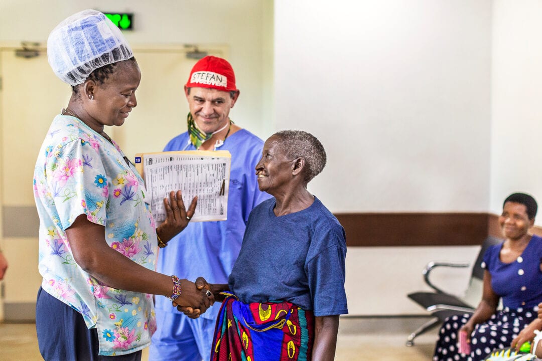 Operation Smile volunteer psychosocial practitioner Cathy Cheonga, left, and volunteer surgeon Dr. Stefan Rawlins of South Africa meet with 79-year-old Flyness before her cleft surgery. Photo: Zute Lightfoot.