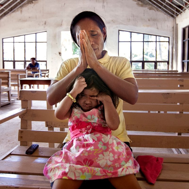 Woman in church praying for help for daughter's cleft lip