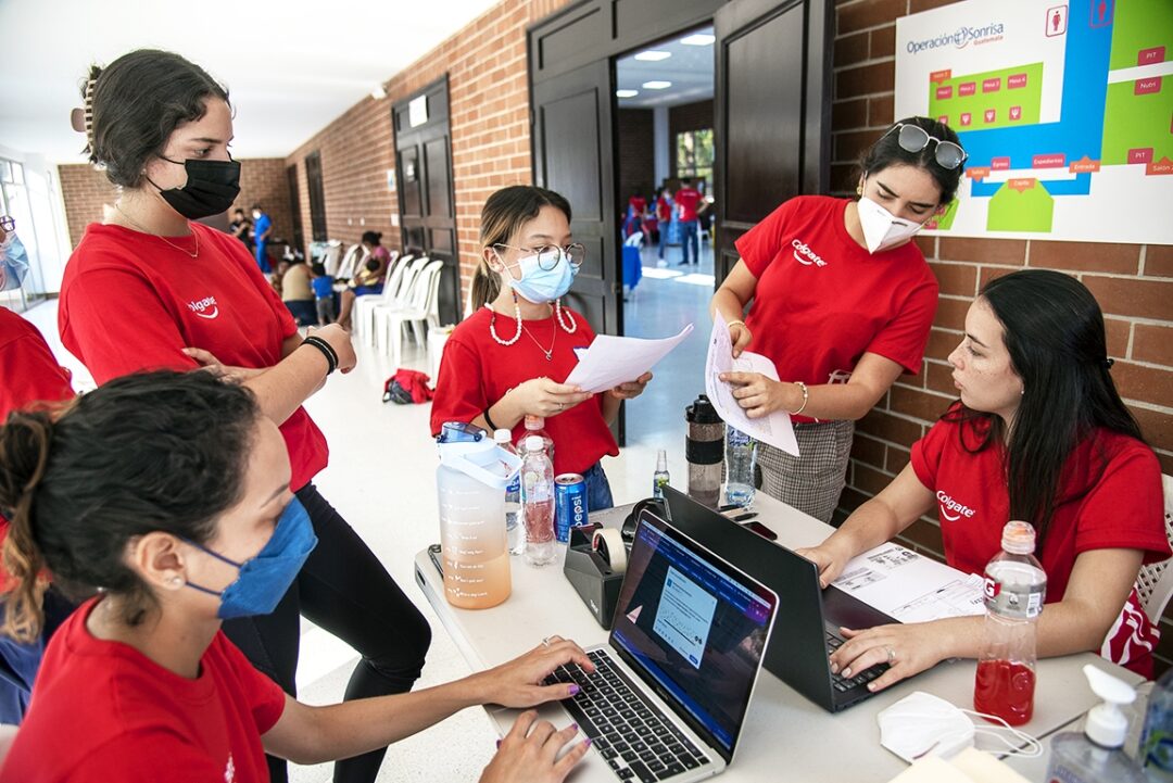 Communications coordinator Anna Lucía Ibarra, left, and Paola Arroyave, right, meet with volunteers to discuss a patient during screening at a 2022 Operation Smile surgical programme in Guatemala City. Photo: Rohanna Mertens.