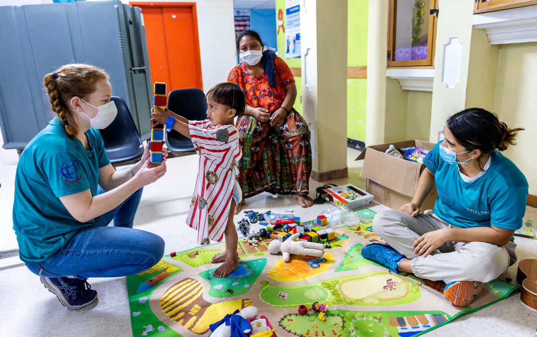 Medical staff play with cleft patient.