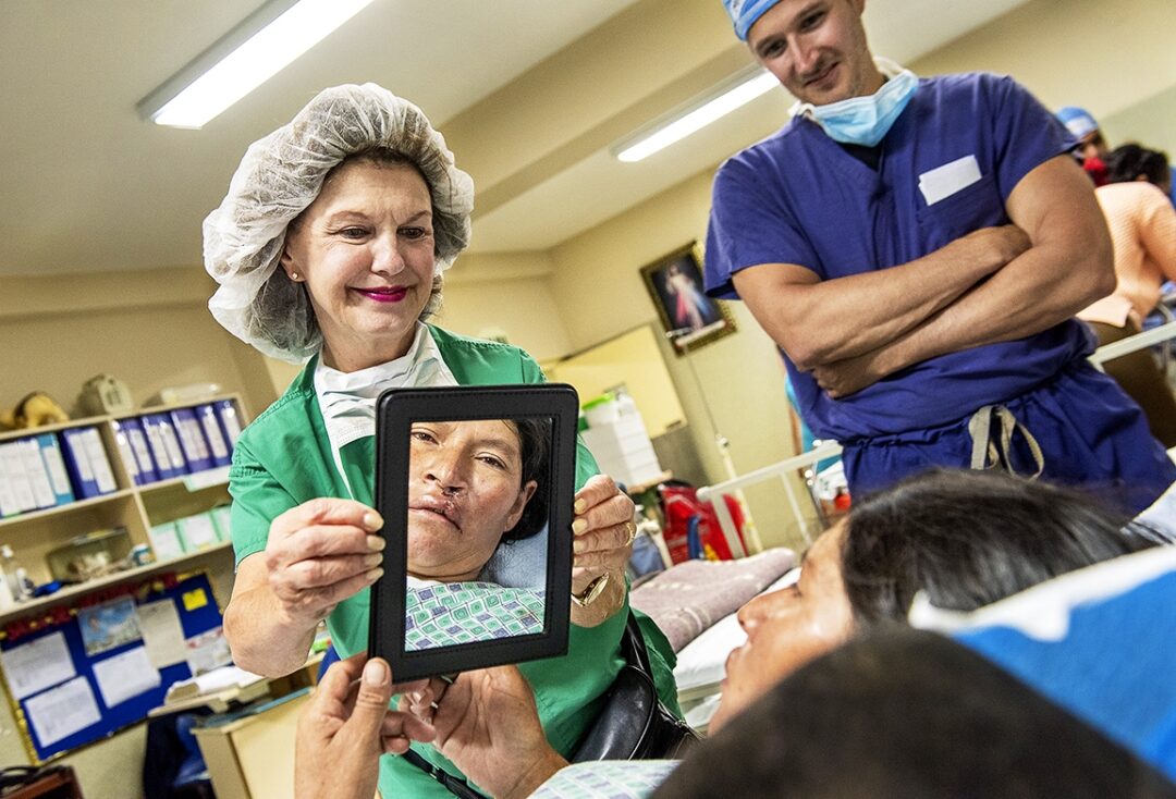 Volunteer clinical coordinator Linda Highfield from the U.S. holds a mirror for Andrea to see her new smile after receiving surgery to repair her cleft lip. Photo: Margherita Mirabella.